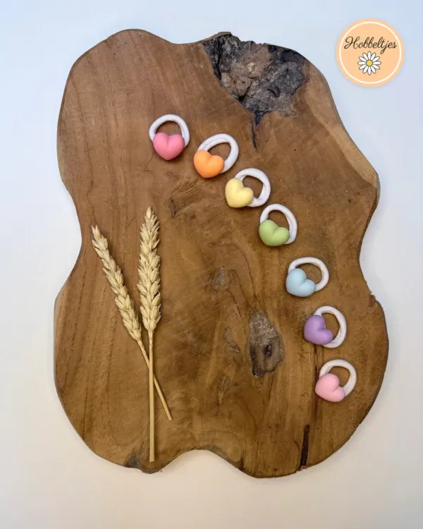 Zeven haarelastiekjes met pastel hartjes in roze, oranje, geel, groen, blauw, lila en roze