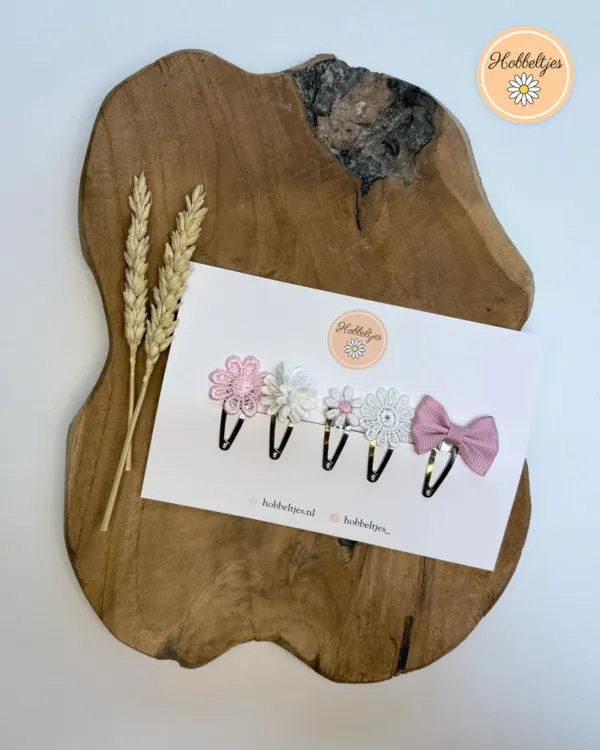 Vijf haarspeldjes met roze en witte bloemen en een roze strik