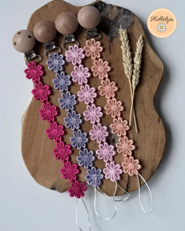 Vier speenkoorden met gehaakte madeliefjes in fuchsia, lila, roze en perzik met houten clips