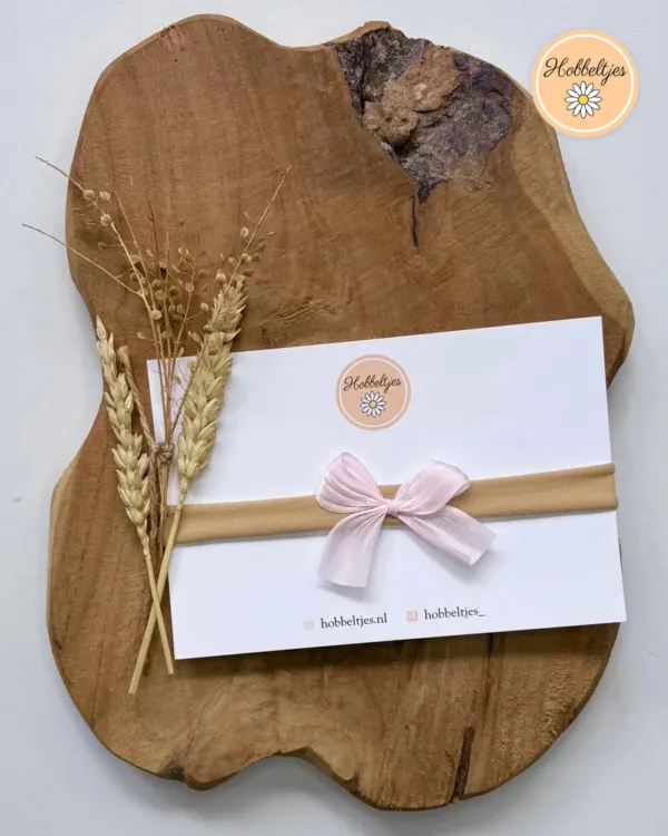 Ein Nude Baby-Haarband mit hellrosa Satinschleife